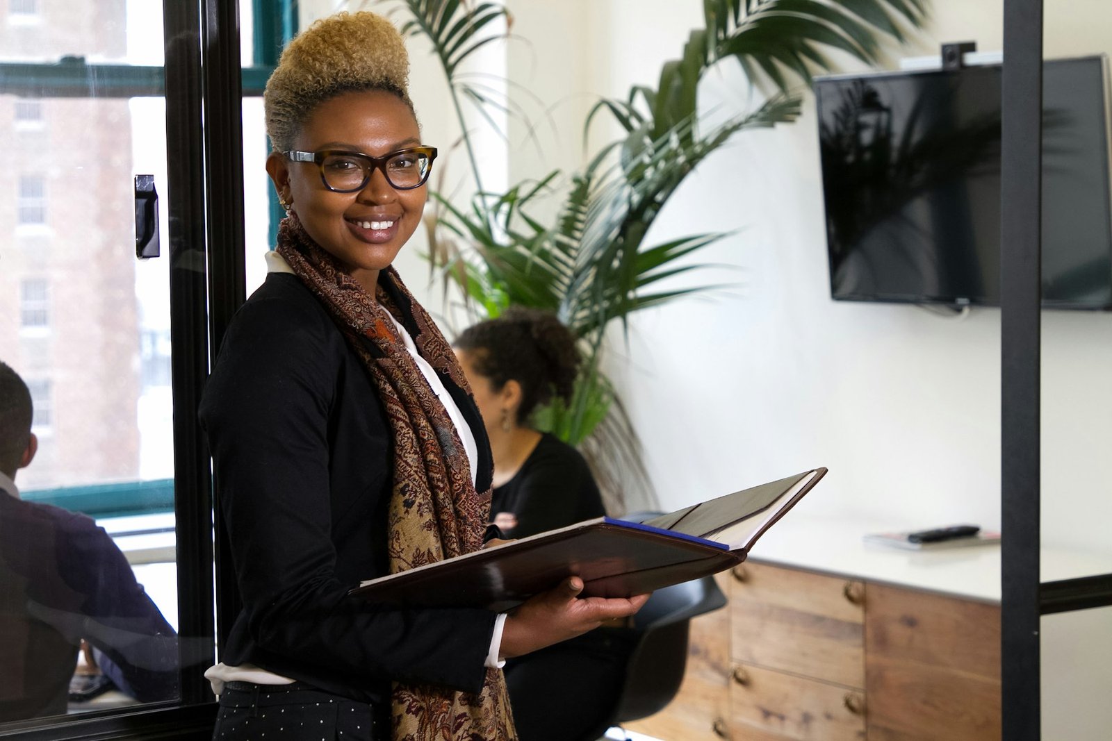 A professional woman holding a binder in a bright modern office