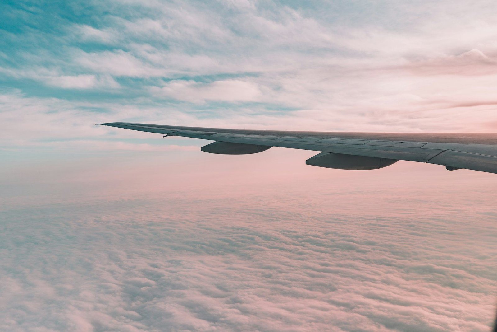 The wing of an aircraft above soft clouds