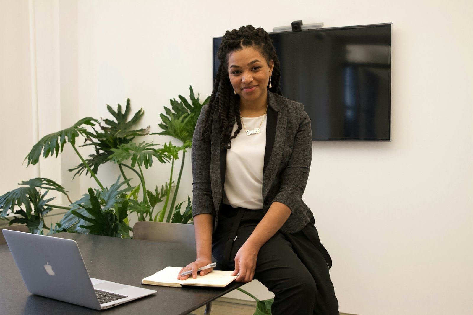 A manager in a grey blazer at her desk, with a laptop and a notebook