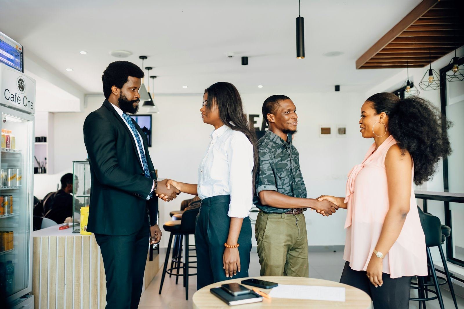 Four colleagues greeting one another with handshakes in a modern office