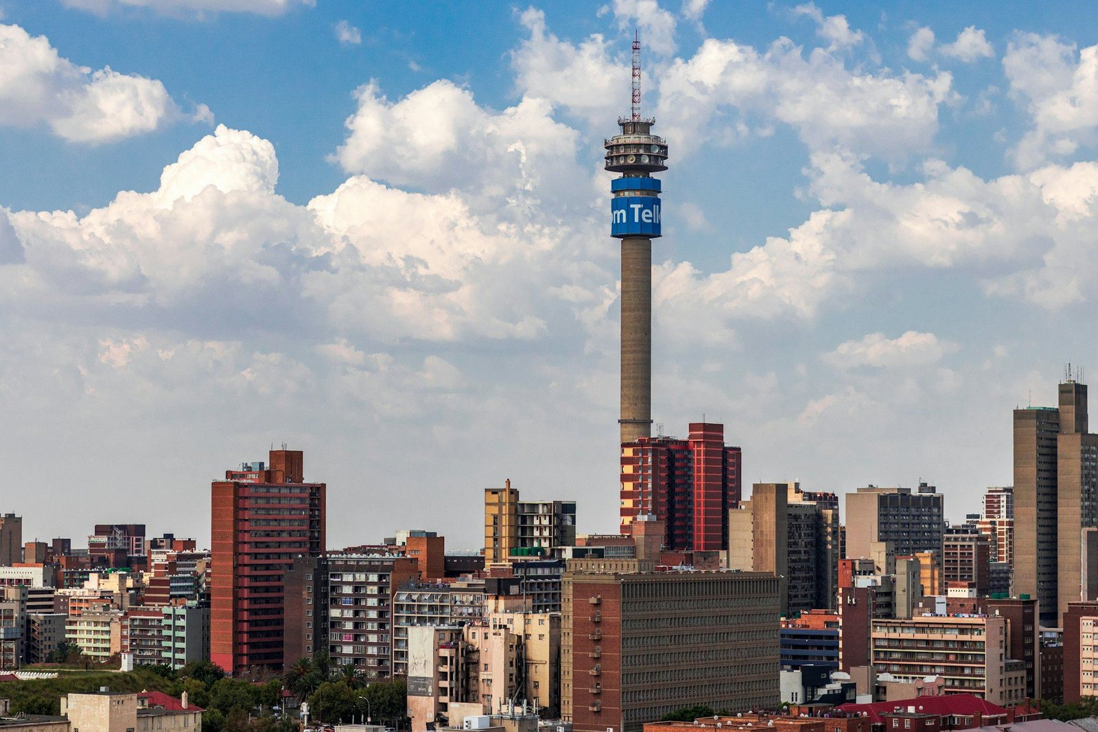 The Johannesburg skyline under a bright sky, with its telecommunications tower rising above the city